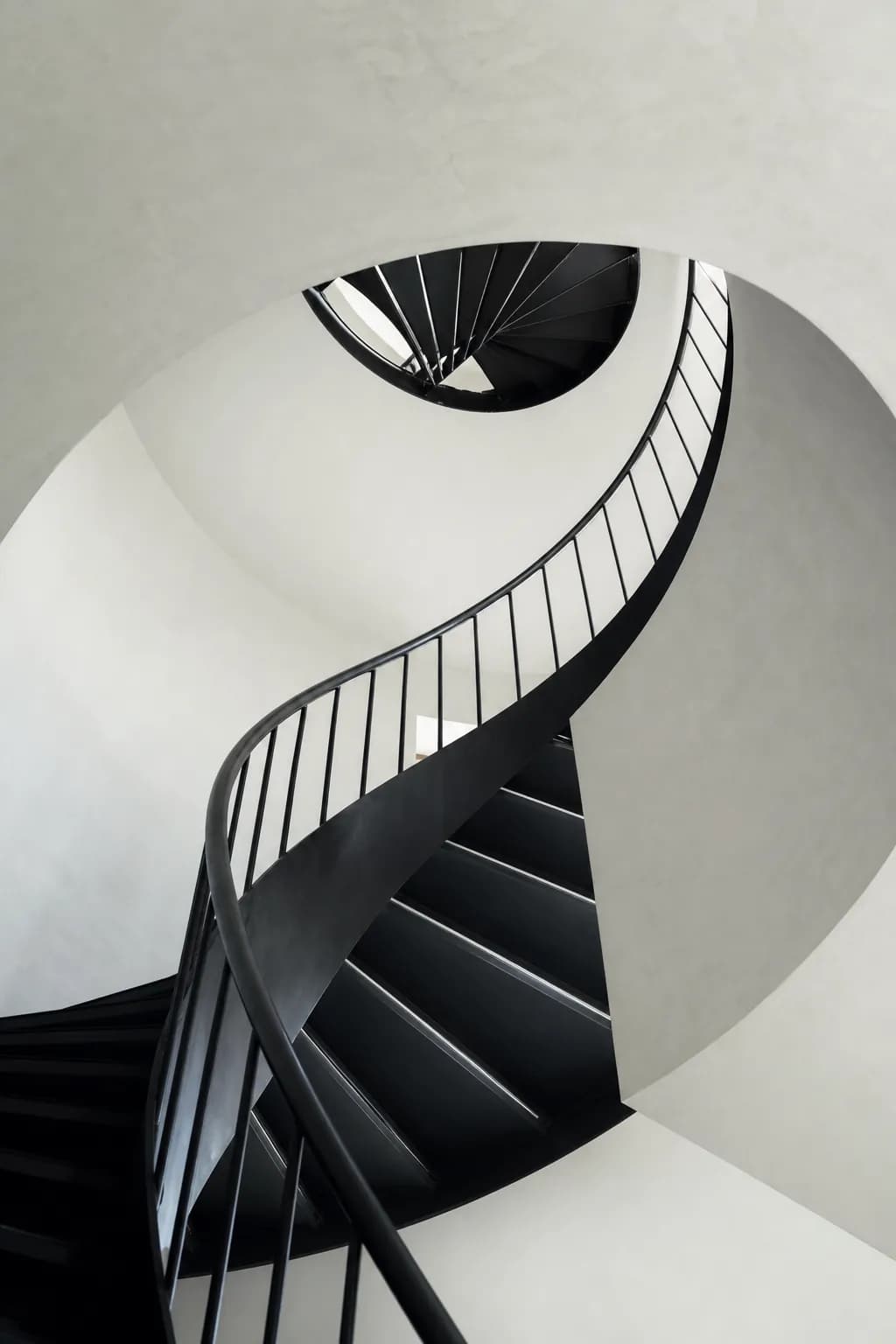 Spiralno stepenište od crnog čelika u belom stepeništu, odozdo